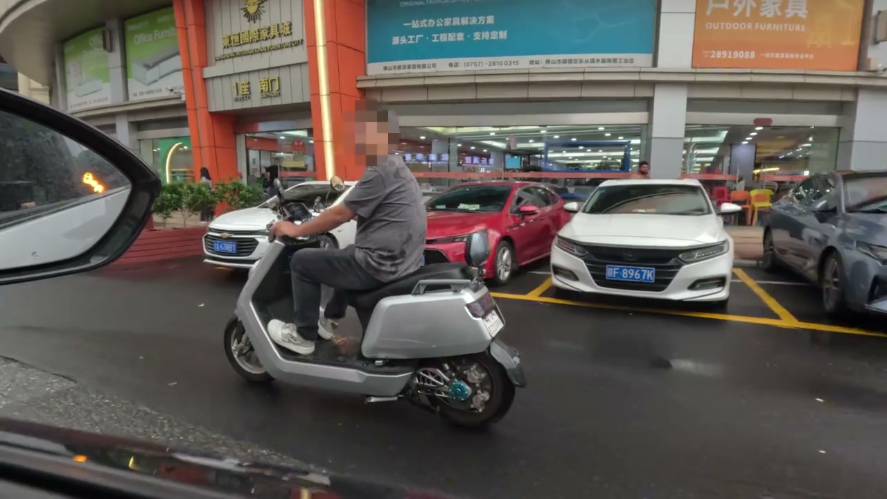 Furniture shops and scooter traffic on a Foshan market street